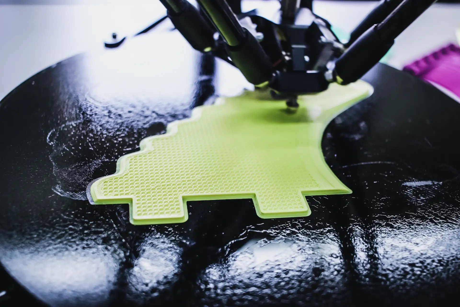 3D printer creating a green, intricate design object.